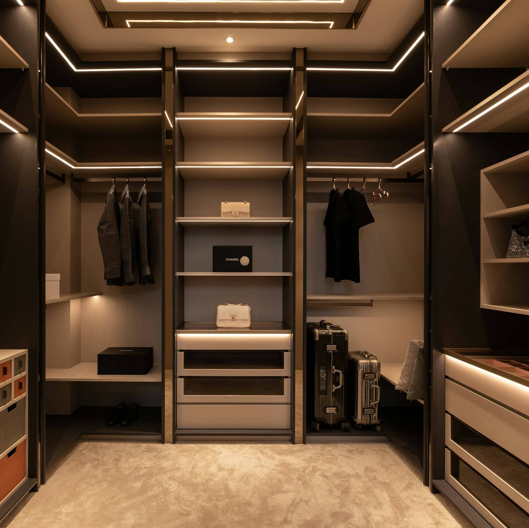 Closet escuro com nichos iluminados, cabideiros e gaveteiros